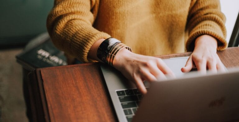 Person i gul trøje surfer på nettet på en bærbar computer