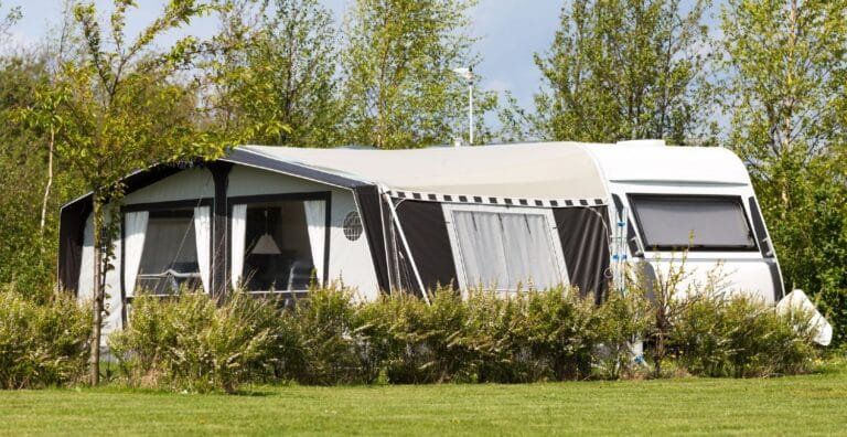 Campingvogn med fortelt på en flot campingplads med solskin