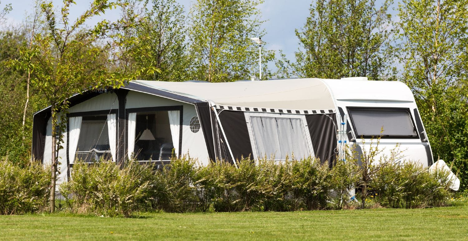 Campingvogn med fortelt på en flot campingplads med solskin