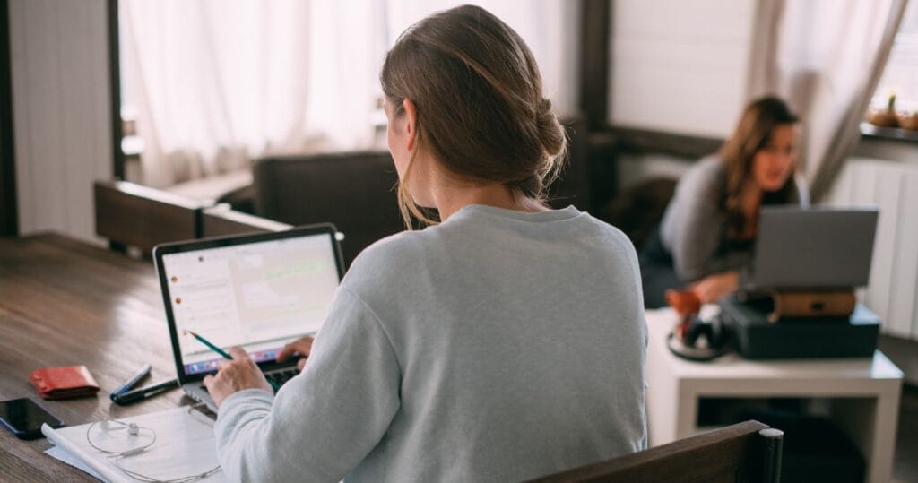 To kvinder arbejder hjemmefra ved spisebordet og sofabordet