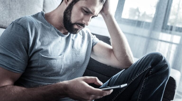 Mand ser på sin telefon og undrer sig over hvem som har ringet til ham