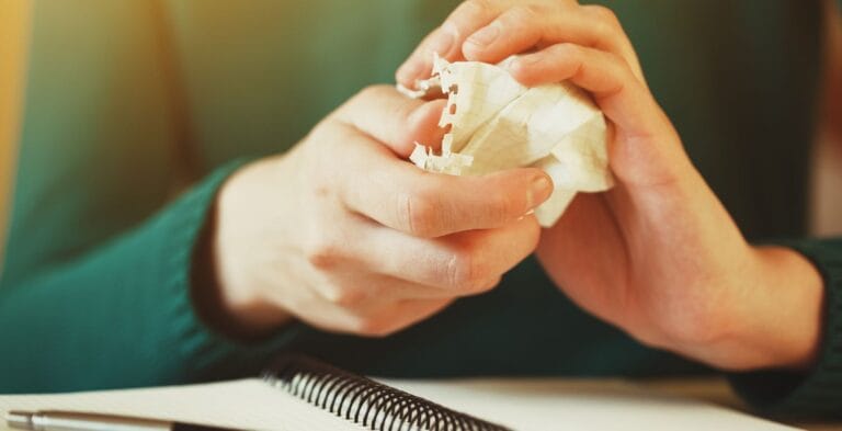 Kvinde i grøn trøje river papir ud af notesblok og krøller det sammen