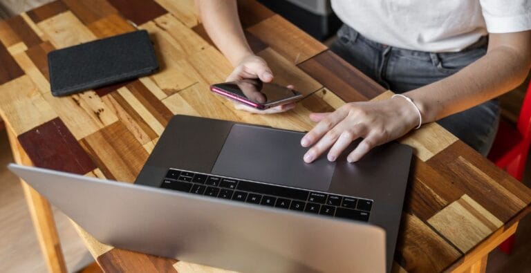Mand i hvid t-shirt surfer på nettet med en Macbook