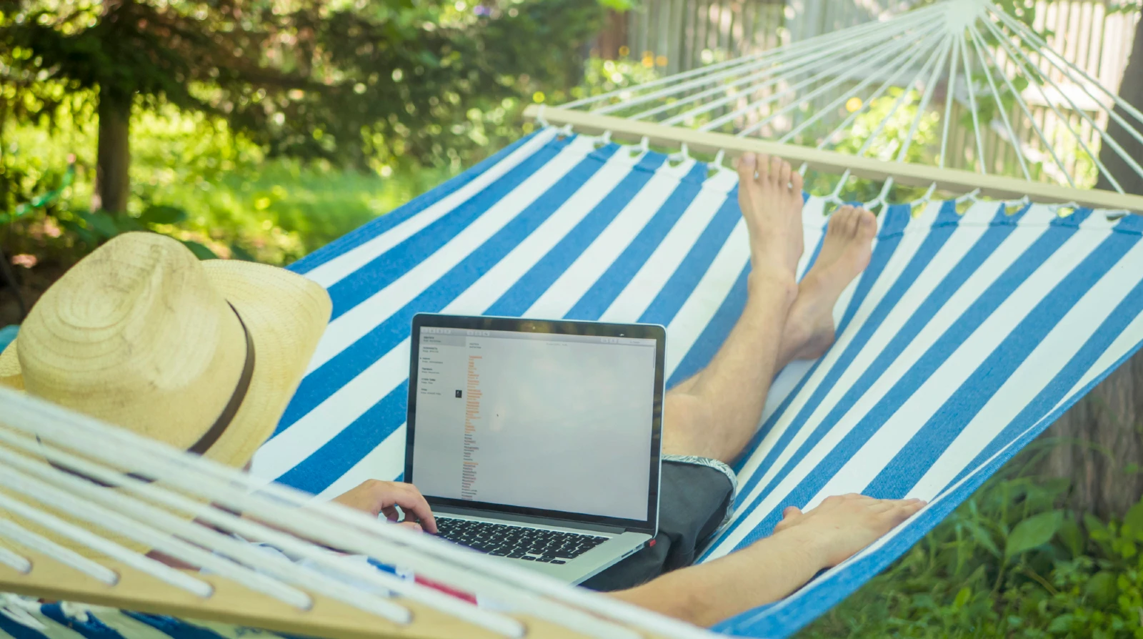 Mand ligger i hængekøjen og bruger sin computer